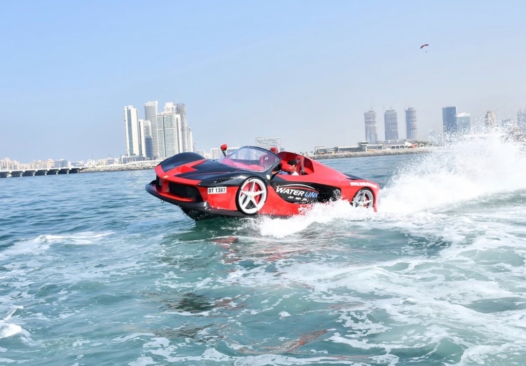 Red jetcar at speed on open water with city skyline in the background